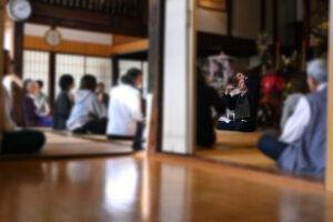 慶學寺に集まった多くの様々な年齢の方々へやさしく身振り手振りで坐禅の説明を解説するGarvey住職のようす。