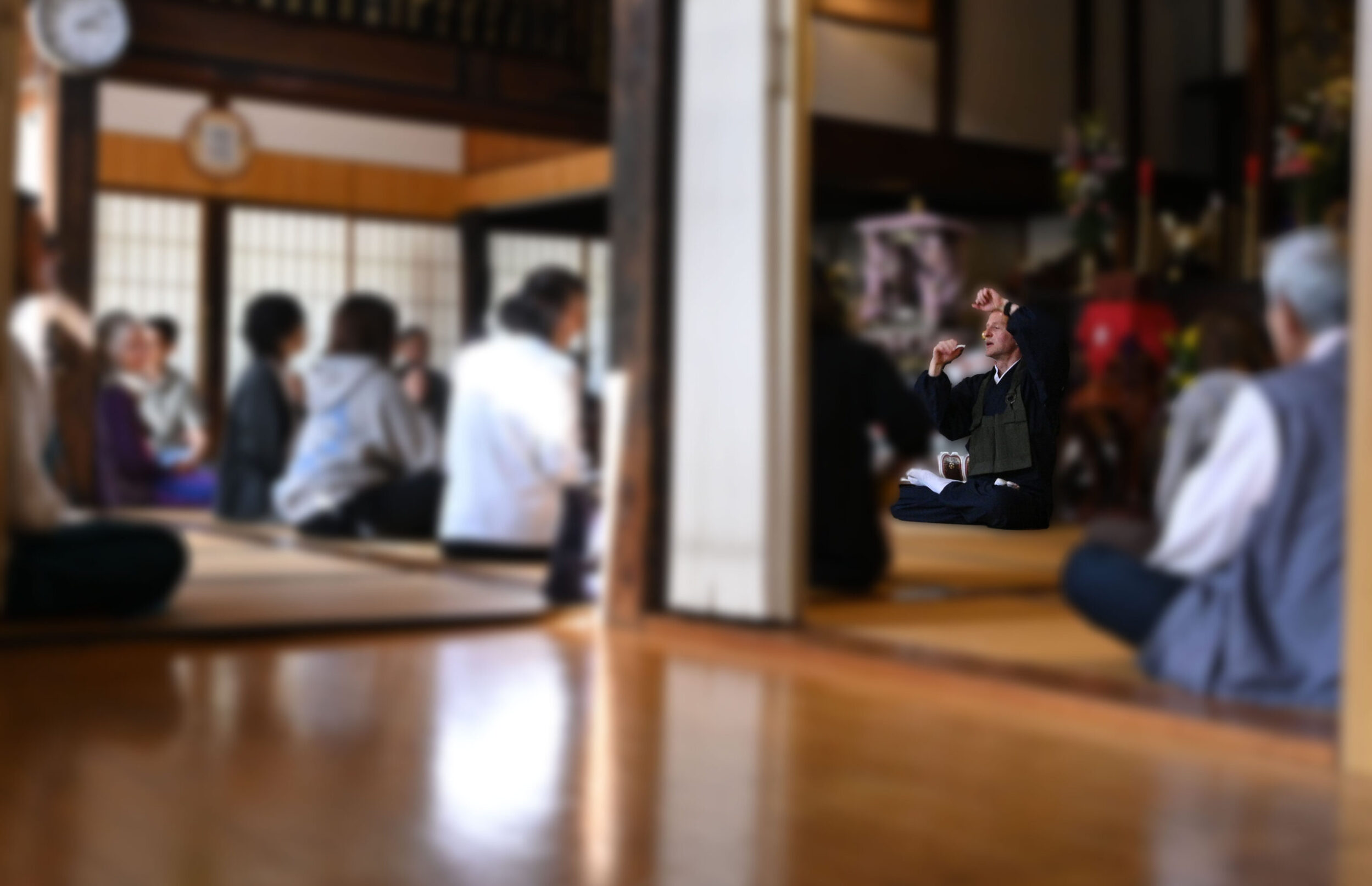慶學寺に集まった多くの様々な年齢の方々へやさしく身振り手振りで坐禅の説明を解説するGarvey住職のようす。