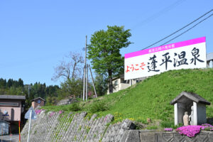 蓬平温泉入口の、よもやま館様駐車場の高台にあるようこそ蓬平温泉の看板とよもやま館様