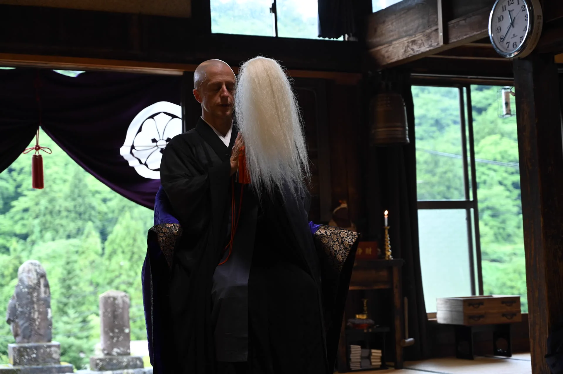 緑の山を望む慶覺寺本堂に立つGarvey住職