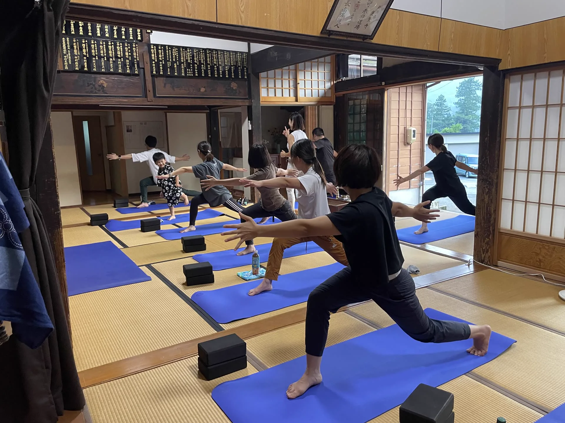 山の景色が見える本堂で寺ヨガを行う参加者
